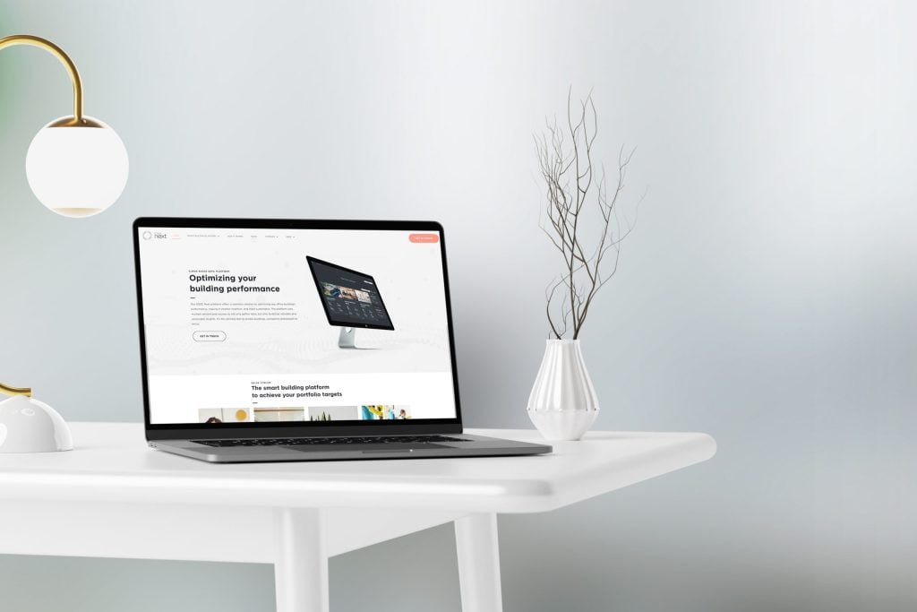 Een moderne werkruimte met een open laptop op een wit bureau en een website over het optimaliseren van prestaties. Naast de laptop staat een vaas met gedroogde takjes. boven het bureau hangt een stijlvolle lamp.